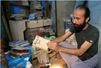 ?? AP ?? Hamzeh AlMaaytah shows off a book at his Mahall Al Maa bookstore in Amman. —