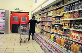  ?? /Reuters ?? An eye on prices: A shopper makes her selection at a grocery store in Joburg. The Reserve Bank, keeping the repo rate unchanged for now, has noted that the inflation outlook faces several risks.
