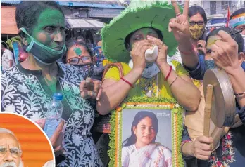  ?? Photo / AP ?? Supporters of Trinamool Congress Party chief Mamata Banerjee, holding a photograph of her, celebrate a lead over the Bharatiya Janata Party of Prime Minister Narendra Modi, left, during the West Bengal state elections in Kolkata, India.