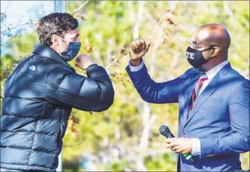  ?? Photog r aphs by Michael Holahan Aug usta Chronicle ?? CANDIDATES Jon Ossoff, left, and the Rev. Raphael Warnock exchange greetings at a rally in Augusta, Ga.