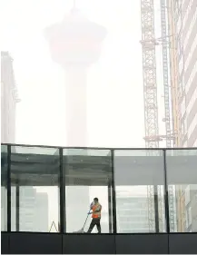  ??  ?? A window washer cleans a Plus-15 downtown, which has been hit with heavy smoke from wildfires in B.C. this week.