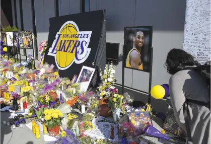  ?? — AP ?? Fans look at a memorial to former Los Angeles Lakers player Kobe Bryant at the NBA basketball team's practice facility in El Segundo, California. Bryant, his 13-year-old daughter, Gianna, and seven others died in a helicopter crash on Sunday.