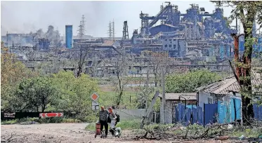  ?? | Reuters ?? PEOPLE transport their belongings near the destroyed Azovstal Iron and Steel Works seen during the Ukraine-Russia conflict in the southern port city of Mariupol, yesterday.