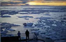  ?? The Associated Press ?? Researcher­s look out from the Finnish icebreaker MSV Nordica as the sun sets over sea ice floating on the Victoria Strait along the Northwest Passage in the Canadian Arctic Archipelag­o.