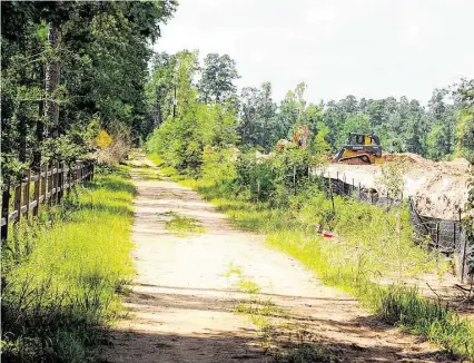  ?? David Hopper ?? Constructi­on started this summer on an apartment complex, right, next to W.G. Jones State Forest, left, at FM 1488.