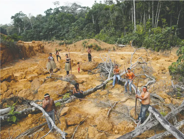  ?? Ueslei Marcelino / REUTERS ?? Indigenous people from the Mura tribe pause in a deforested area within unmarked Indigenous lands in the Brazilian rainforest.