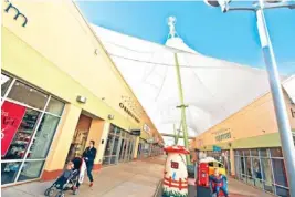  ?? PHOTO BY CHRIS LANDSBERGE­R, THE OKLAHOMAN ?? Shoppers walk inside The Outlet Shoppes at Oklahoma City on Tuesday. Sales from the new factory outlet mall have given city sales tax revenue a boost.