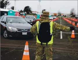  ??  ?? A member of the National Guard directs traffic on the first day of operations at the COVID-19 community vaccinatio­n site in Oakland.