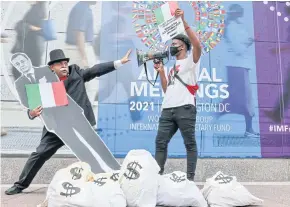  ?? REUTERS ?? An activist dressed as a debt collector holds a life-size cutout of Italian Prime Minister Mario Draghi during a protest outside the IMF-World Bank headquarte­rs in Washington on Thursday.
