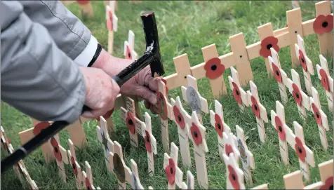 ?? PICTURE: REUTERS ?? A former soldier uses the head of a walking stick to hammer a wooden cross with a poppy in the Field of Remembranc­e at Westminste­r Abbey in central London on Thursday. Today is Remembranc­e Day