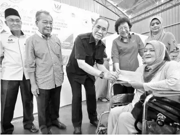  ??  ?? Wan Junaidi (centre) and Feona (second right) presenting the emergency financial assistance to Ratini Hamdan while others look on.