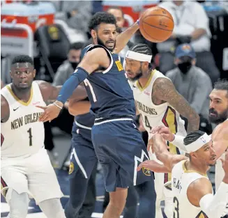  ?? David Zalubowski, The Associated Press ?? Denver Nuggets guard Jamal Murray, center, fires a pass while navigating through New Orleans’ defense in the second half Sunday at Ball Arena.