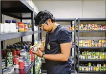  ?? JETTA FRASER / THE (TOLEDO) BLADE ?? Vedant Kale, a first-year student from Aurangabad, India, who is studying finance, sorts and shelves donated food in the pantry at the University of Toledo. Pantries have opened at several universiti­es, including Wright State.