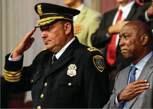  ?? Brett Coomer / Houston Chronicle ?? El jefe de la policía de Houston, Art Acevedo (izq.) y el alcalde de la ciudad Sylvester Turner escuchan juntos las estrofas del himno nacional durante la ceremonia de graduación de la Clase de Cadetes 232 del HPD en Greater Grace Outreach Church, el...