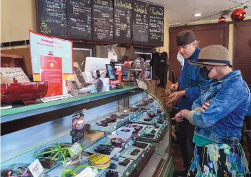  ?? DAMIAN DOVARGANES/ASSOCIATED PRESS ?? Jeffray Gardner, owner of Marsatta Chocolate explains his artisan chocolates to customer Katherine Trontman at his company’s flagship store in Torrance, California, in March. Restaurant­s and delivery companies remain uneasy partners, haggling over fees and struggling to make the service profitable for themselves and each other.