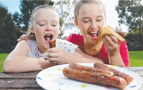  ?? Picture: YURI KOUZMIN ?? CHOOSE CAREFULLY: Tallulah and Matisse Eabry, 11, enjoying a traditiona­l sausage snack.