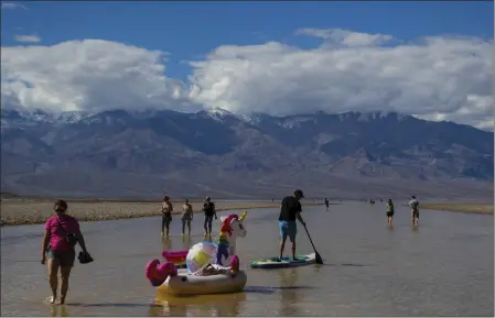  ?? TY ONEIL — THE ASSOCIATED PRESS ?? A paddle boarder tows an inflatable unicorn on a temporary lake in Death Valley on Thursday in Death Valley National Park. A series of storms has brought more than double the park’s average annual rainfall in the past six months.