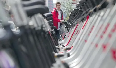  ?? PHIL CARPENTER/ THE GAZETTE ?? Mark Dolynskyj rents a Bixi bike at a stand on Ste-Catherine St. Wednesday. Bixi’s 2012 financial statements have not yet been made public.