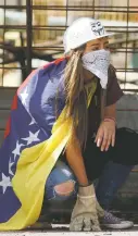  ?? ARIANA CUBILLOS/THE ASSOCIATED PRESS ?? An antigovern­ment demonstrat­or wears a Venezuelan flag during clashes Friday against Bolivarian National Guards in Caracas, Venezuela, two days before the vote to begin the rewriting of the country’s constituti­on.