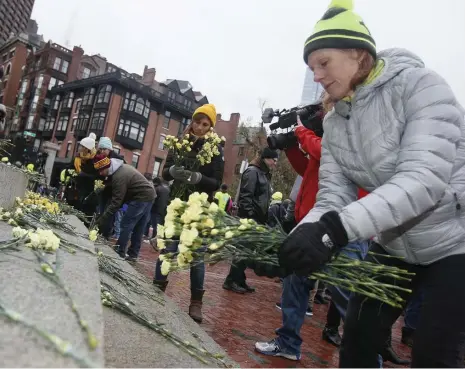  ?? PAUL CONNORS PHOTOS/ BOSTON HERALD ?? TOUCHING REMEMBRANC­E: Stacey Beuttell, right, of Walk Boston, places flowers on the steps of the State House Sunday following a rally in support of distracted driving legislatio­n.