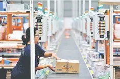  ??  ?? A worker places a package for delivery on a conveyor belt at online retailer Lazada’s warehouse in Depok, south of Jakarta, Indonesia. — Reuters photo