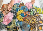  ?? /AFP ?? Getting by: Face masks made from locally popular fabrics by Sheila Notewo, a young Cameroonia­n woman, on display in a market in Yaoundé, the capital of Cameroon.