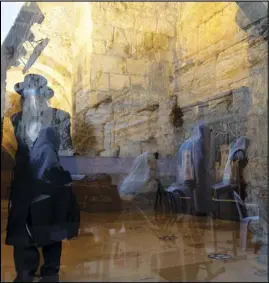  ?? ASSOCIATED PRESS ?? Ultra Orthodox Jewish men are seen reflected in a window Wednesday as they pray ahead of the Jewish new year at the Western Wall, the holiest site where Jews can pray in Jerusalem’s old city.