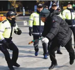  ??  ?? ... A protester, taking part in a “cleaning the road around the presidenti­al Blue House” demonstrat­ion against President Park Geun-Hye, runs to avoid policemen in Seoul yesterday. Prosecutor­s are investigat­ing allegation­s that Park’s confidant Choir...