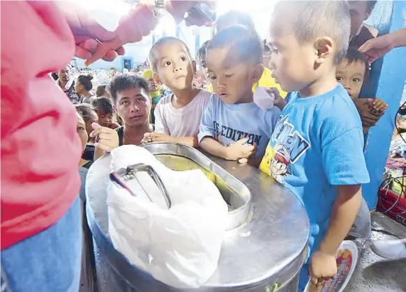  ??  ?? Children at the Maria Cristina Evacuation Center are treated to ice cream.