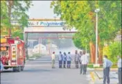  ?? PTI PHOTO ?? Firefighte­rs stand outside the LG Polymers factory as styrene vapours linger at a distance.