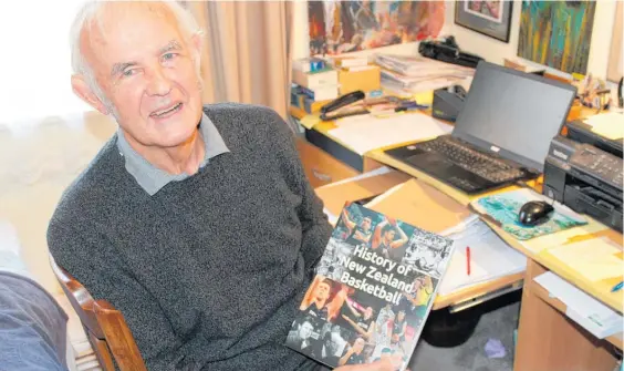  ?? Photo / David Haxton ?? Roger Booth with a copy of History of New Zealand Basketball.