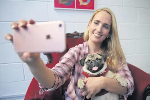  ??  ?? PHOTOGENIC: Aida Martinez, owner of Pugs and Pals cafe, says owners love their dogs’ saggy faces and big eyes.