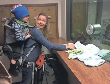  ?? JACOB CARPENTER / MILWAUKEE JOURNAL SENTINEL ?? Meagan Schultz talks to her 2-year-old son, Will, Friday as she leaves a diaper at the front desk of the Milwaukee County Sheriff's Office. The diapers were a symbolic reference to the death of a newborn at the county jail.