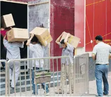  ?? AP ?? Workers carry boxes of lights at a renovation site in Beijing on Tuesday. China says it will match threatened U.S. tariffs.