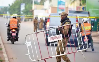  ??  ?? A Burkina Faso policeman establishe­s a barrier on a street following a deadly attack in Ouagadougo­u on Monday. (AFP)