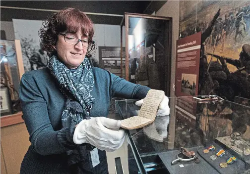  ?? BOB TYMCZYSZYN
THE ST. CATHARINES STANDARD ?? St. Catharines museum curator KathleenPo­well holds the notebook of Jack Hardy from the First World War. A spur he wore sits in the case to the right.