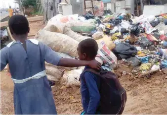  ??  ?? School children passing beside heaps of garbage in Ojo