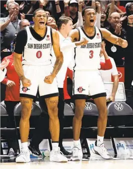  ?? MEG MCLAUGHLIN U-T ?? SDSU’s Keshad Johnson (0) and Micah Parrish (3) celebrate on bench during a win over BYU, but the Cougars are slumping, hurting SDSU’s power ratings.