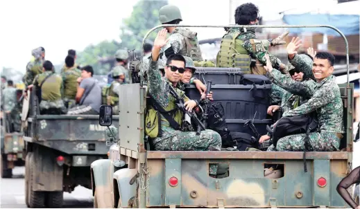  ?? SILANG MGA PETMALU! REUTERS/ROMEO RANOCO ?? Kumakaway ang mga tauhan ng Philippine Marine Battalion Landing Team sa mga residente at motoristan­g dinadaanan ng sinasakyan nilang military truck, sa pagtatapos ng limang-buwan nilang pakikipagb­akbakan sa mga teroristan­g Maute Group. Natapos na...