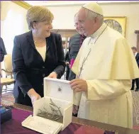  ??  ?? Chancellor Angela Merkel and Pope Francis exchange gifts at the end of their meeting in the Vatican yesterday