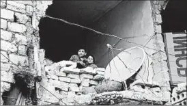  ?? ALEXANDER KOTS/KOMSOMOLSK­AYA PRAVDA ?? Children peer from a partially destroyed home in war-torn Aleppo, Syria, earlier this year.