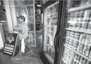  ?? Melissa Phillip / Staff photograph­er ?? Argie Arteaga restocks to-go beer Thursday at 8th Wonder Brewery and Distillery. The leisure and hospitalit­y industry has borne the brunt of the fourth wave of COVID-19.