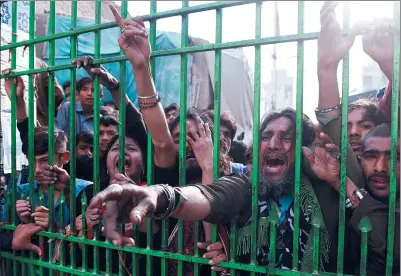  ?? SIF HASSAN / AGENCE FRANCE-PRESSE ?? Mourners gather outside the closed gate of a shrine in Sehwan, Pakistan, after a terrorist bombing left 88 dead and hundreds wounded.