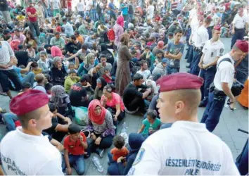  ?? — Reuters file photo ?? Hungarian police officers watch migrants outside the main Eastern Railway station in Budapest, Hungary.