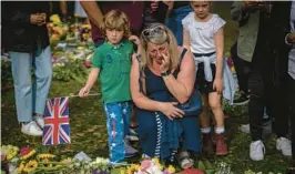  ?? EMILIO MORENATTI/AP ?? A woman weeps Saturday amid flowers and messages for Queen Elizabeth II, a rock in turbulent times, at the Green Park memorial near Buckingham Palace in London.