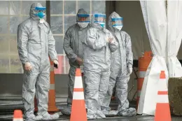  ?? JOHN MINCHILLO/AP ?? Medical personnel await patients for coronaviru­s testing in March 2020 at a facility at Glen Island Park in New Rochelle, New York.