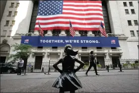  ?? (AP) ?? The Fearless Girl statue stands in front of the New York Stock Exchange in New York in this July photo. The S&P 500 and the Dow Jones Industrial Average ended 2020 at record highs Thursday on Wall Street, ending a year that saw a breathtaki­ng nose dive in markets in the spring as the coronaviru­s took hold, followed by steady gains in the months that followed.