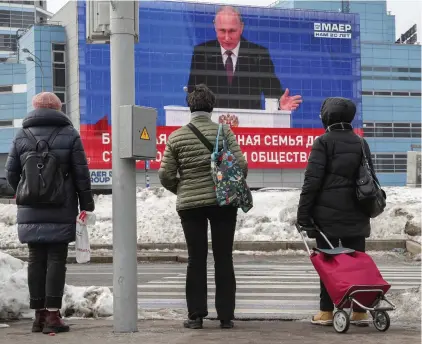  ?? ?? Stopped in their tracks: Moscow shoppers watch Putin’s ‘Big Brother-style’ broadcast yesterday