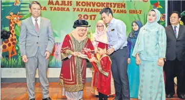  ??  ?? Juma’ani (second left) presents a scroll to a child who graduated at the 7th Graduation Ceremony of Taska Tadika Yayasanku Sayang at Wisma Adenan, Sarawak Foundation yesterday. With her on stage are Azmi (left) and others.