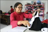  ?? (AP/Firdiadia Lisnawati) ?? Ni Luh Erniati, who lost her husband in a 2002 Bali bombing, folds clothing Oct. 4 as she runs her tailoring business in Bali.